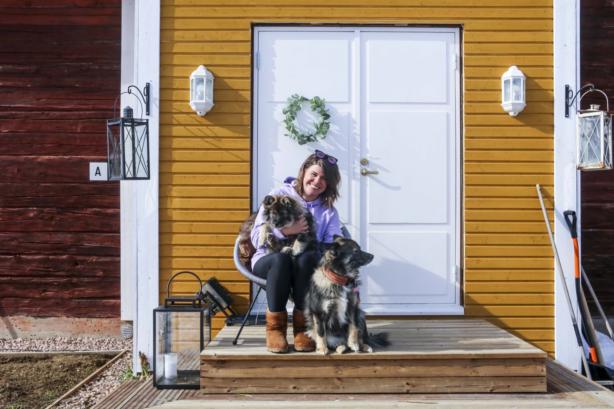 Inari Fernández kotinsa edessä kahden koiransa kanssa Vuojärvellä (kuva: Liisa Kuittinen)